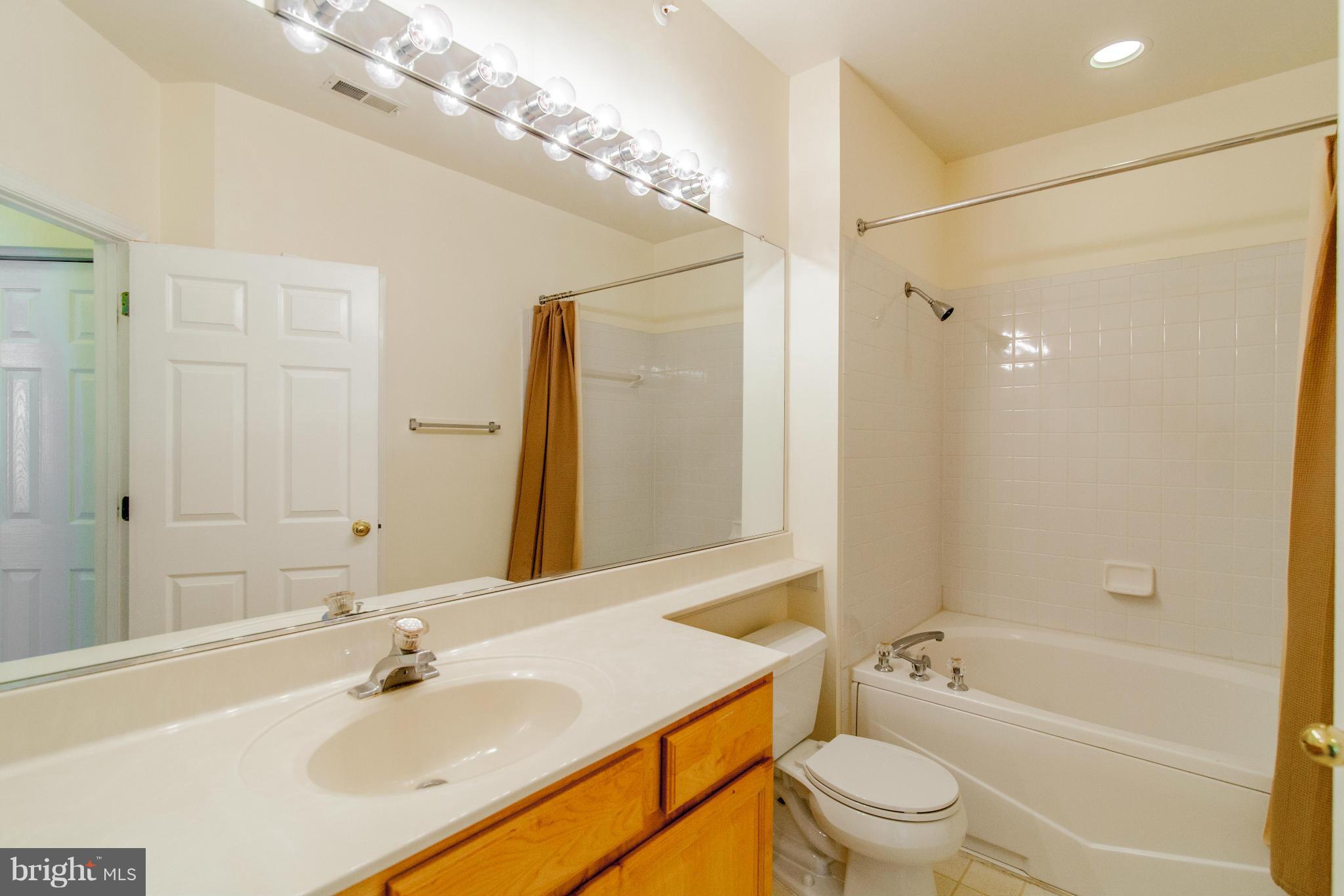 12008 Amber Ridge Circle, Unit A301 Germantown, MD 20876 - Photo 12 of 22 a bathroom with a bathtub shower sink vanity and toilet