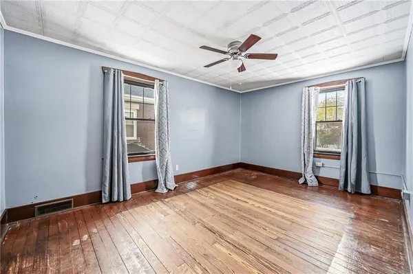 an empty room with wooden floor closet and windows