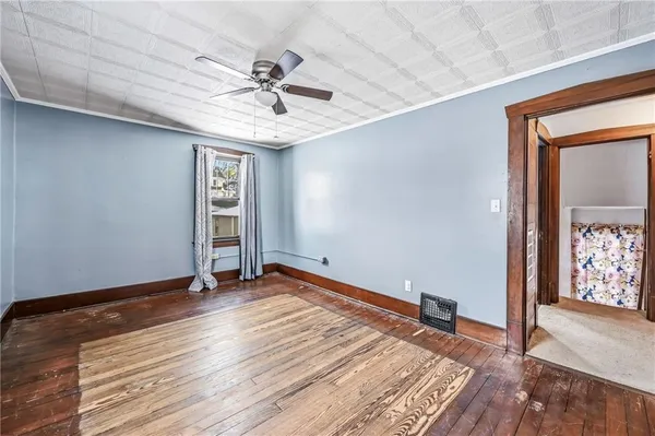 a view of an empty room with wooden floor and a ceiling fan