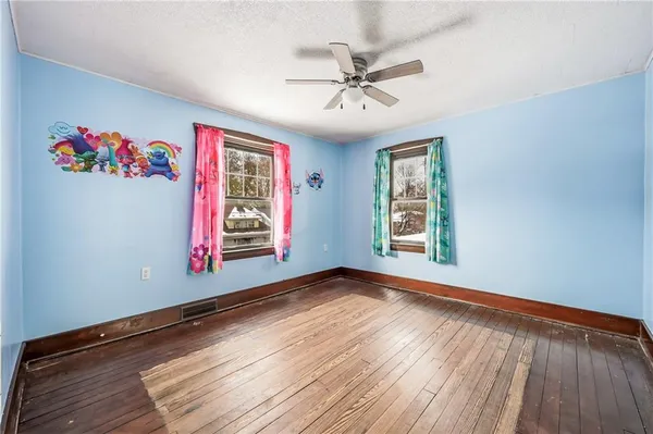 a view of an empty room with a window and wooden floor