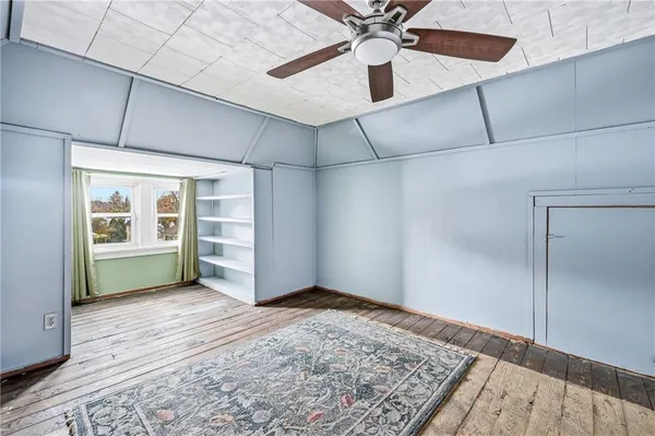 a view of an empty room with a window and wooden floor