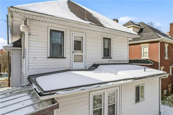 a view of a house with a barbeque and wooden stairs