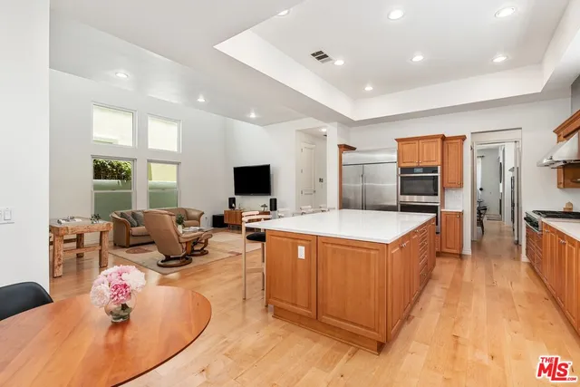 a living room with stainless steel appliances furniture and a kitchen view
