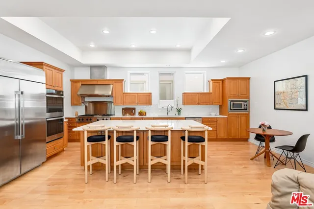 a open kitchen with stainless steel appliances granite countertop a stove a sink a dining table and chairs with wooden floor