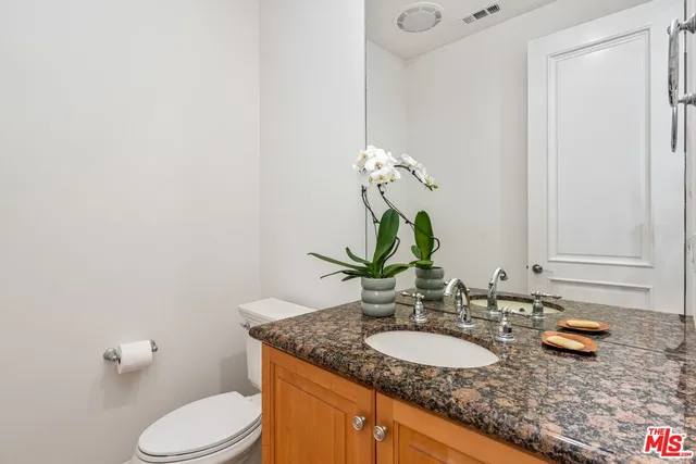 a bathroom with a granite countertop toilet sink and mirror
