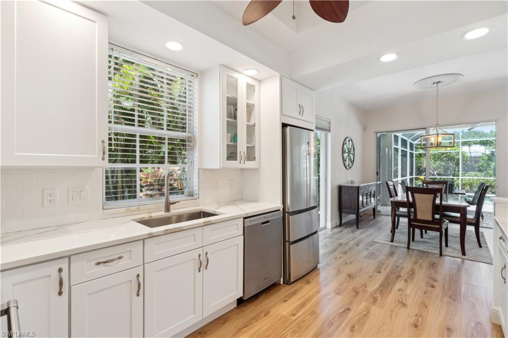 5049 Fairhaven Lane Naples, FL 34109 - Photo 11 of 46 a kitchen with stainless steel appliances granite countertop a refrigerator a sink dishwasher a dining table and chairs with wooden floor