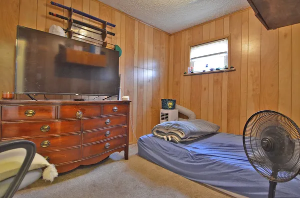 a bedroom with a bed and a flat tv screen on dresser