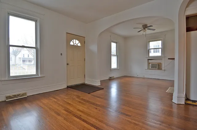 an empty room with wooden floor and windows