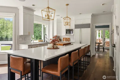 a kitchen with stainless steel appliances a dining table chairs and a large window