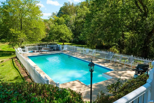 a view of a swimming pool with a patio and fire pit