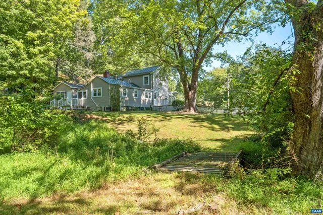 a view of a house with a big yard and large trees
