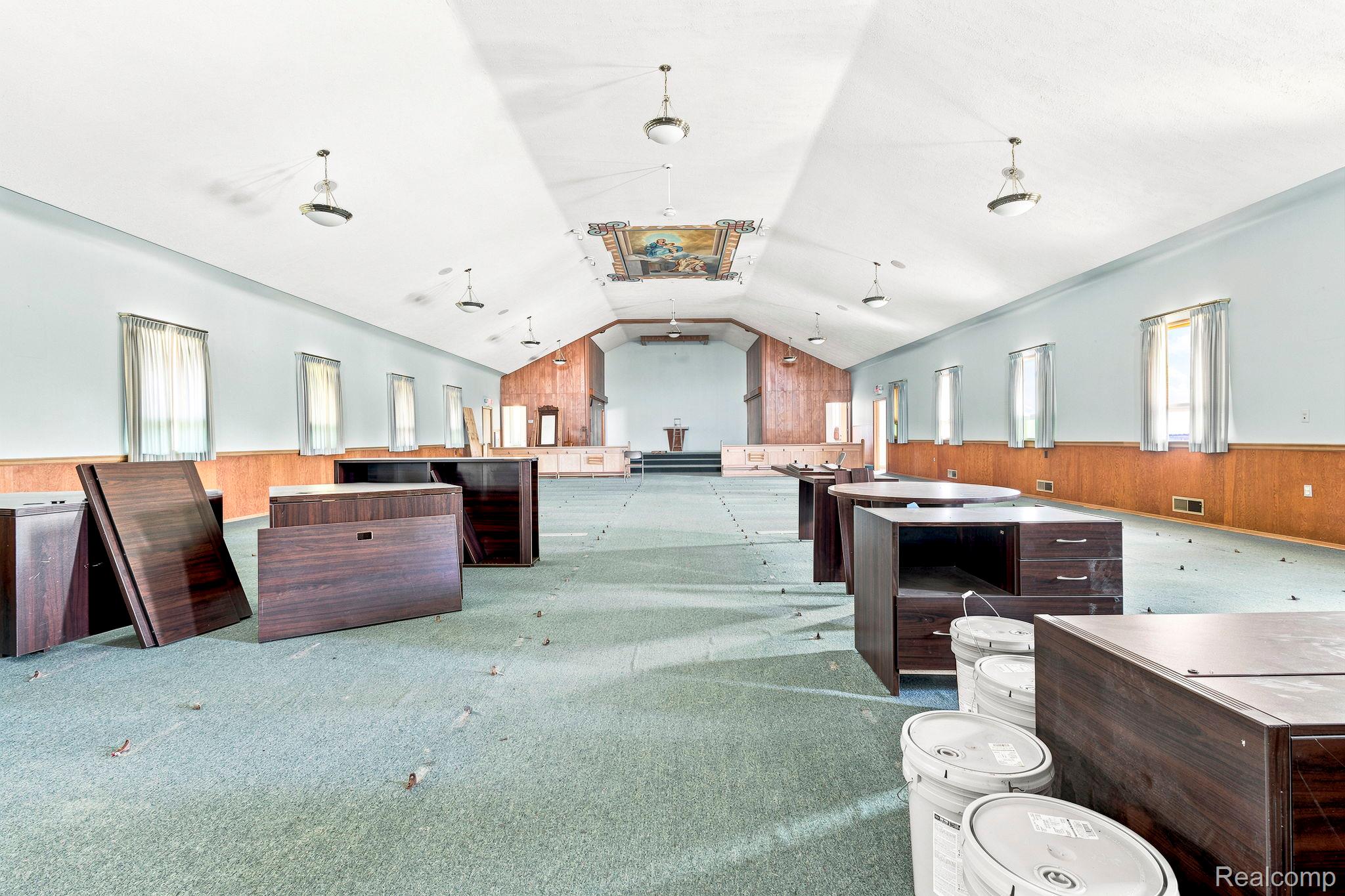 9735 Dolan Road Columbus, MI 48063 - Photo 42 of 63 Large open-concept space featuring a vaulted ceiling with pendant lighting, multiple windows, and wood paneling along the lower walls