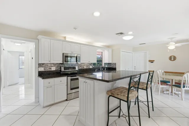 a kitchen with white cabinets and sink