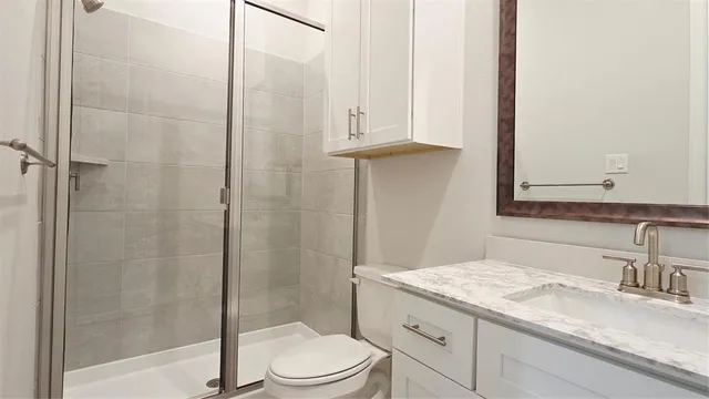 a bathroom with a granite countertop sink a toilet and shower