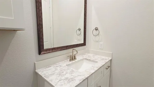 a bathroom with a granite countertop sink and a mirror