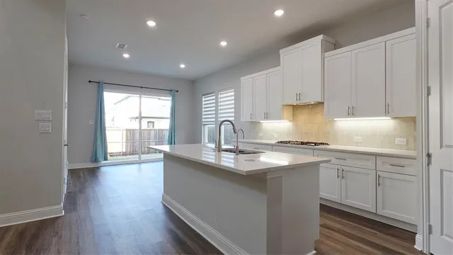 a kitchen with stainless steel appliances granite countertop a sink a stove and a wooden floors