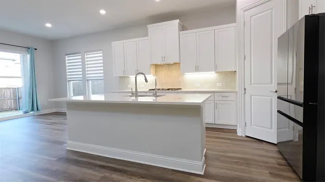 a kitchen with kitchen island granite countertop a refrigerator and a sink