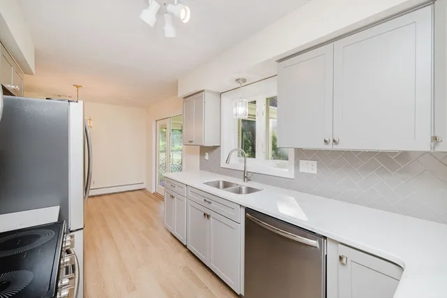 a kitchen with a sink cabinets stainless steel appliances and a window