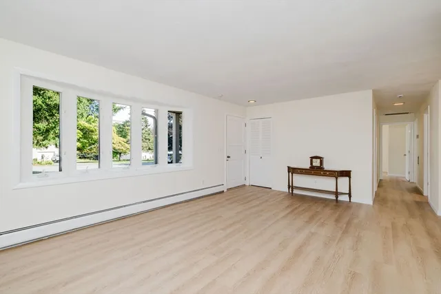 a view of an empty room with window and wooden floor