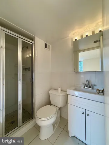 a bathroom with a toilet a sink a glass door and shower