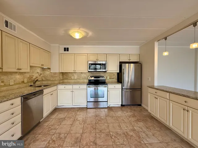 a kitchen with kitchen island granite countertop a stove sink and refrigerator