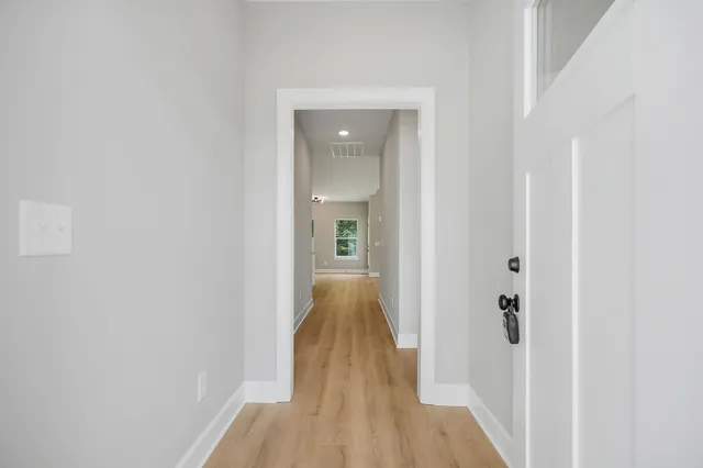 a view of a hallway with wooden floor and a bathroom