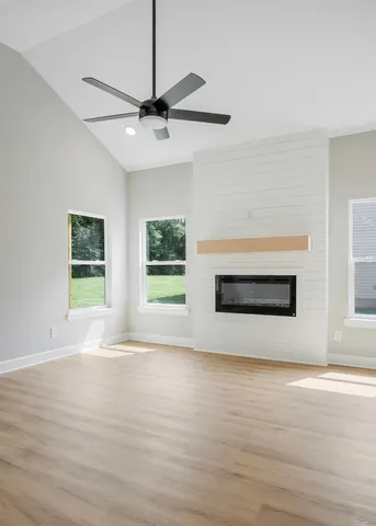 a view of empty room with wooden floor and fan