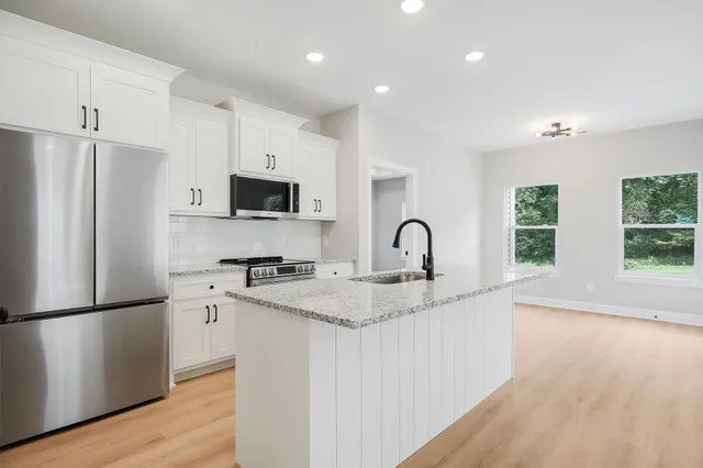a kitchen with stainless steel appliances granite countertop a refrigerator sink and white cabinets