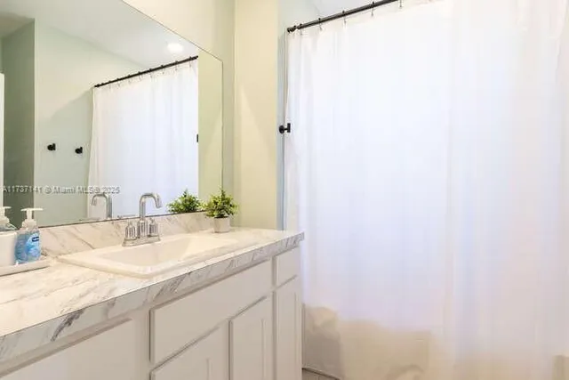 a bathroom with a granite countertop sink and a mirror
