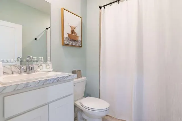 a bathroom with a granite countertop sink mirror vanity and toilet