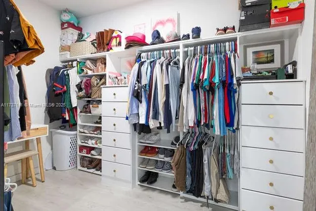 a view of walk in closet with clothes and shoes
