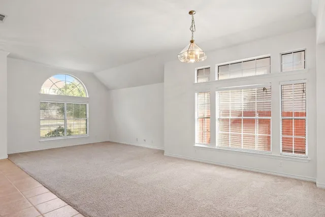 an empty room with windows and ceiling fan