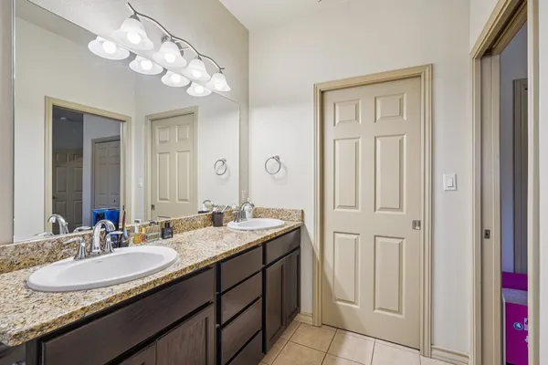a bathroom with a granite countertop sink a light fixture and a mirror