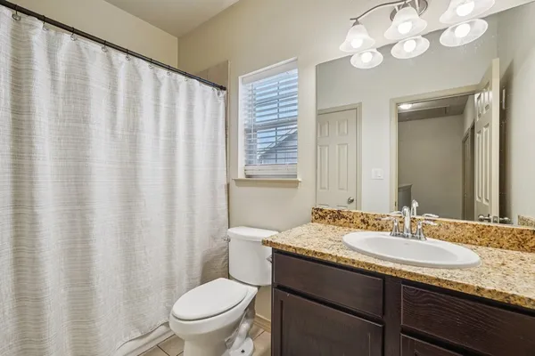 a bathroom with a granite countertop sink a toilet and a mirror
