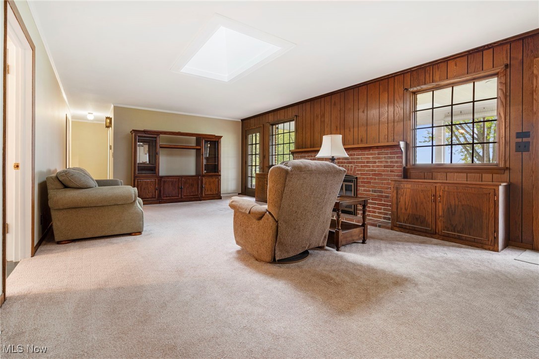 14265 Reeder Avenue Northeast Alliance, OH 44601 - Photo 8 of 39 Living room featuring light colored carpet, a skylight, wooden walls, and crown molding