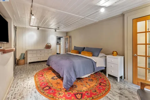 a bedroom with a bed and a flat tv screen on dresser