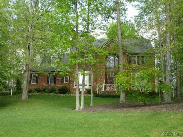 a view of house in front of a big yard with large trees