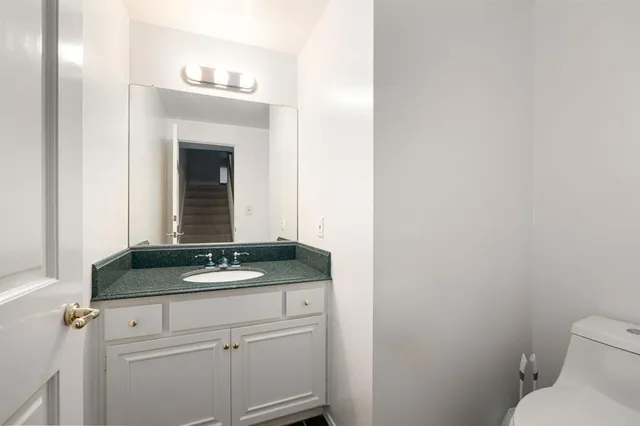 a bathroom with a granite countertop sink and a toilet