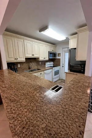 a kitchen with granite countertop a stove a sink and a microwave