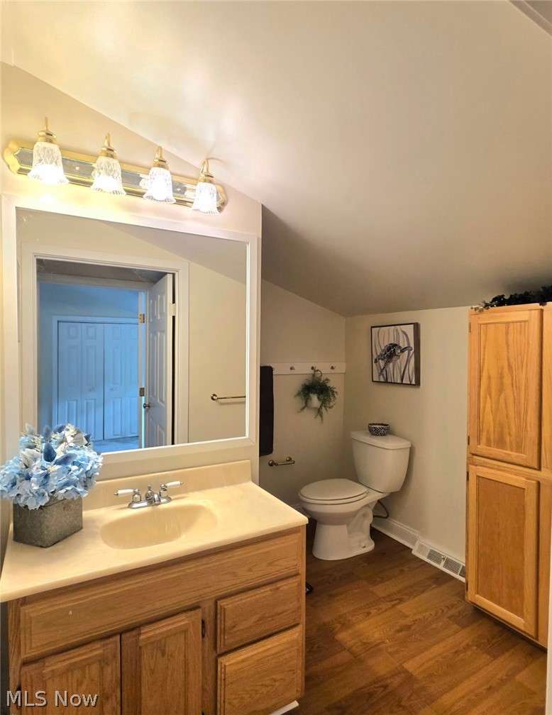398 North Chillicothe Road Aurora, OH 44202 - Photo 33 of 39 Bathroom featuring wood-finish flooring, a vanity with an integrated sink, a built-in medicine cabinet, and a white toilet