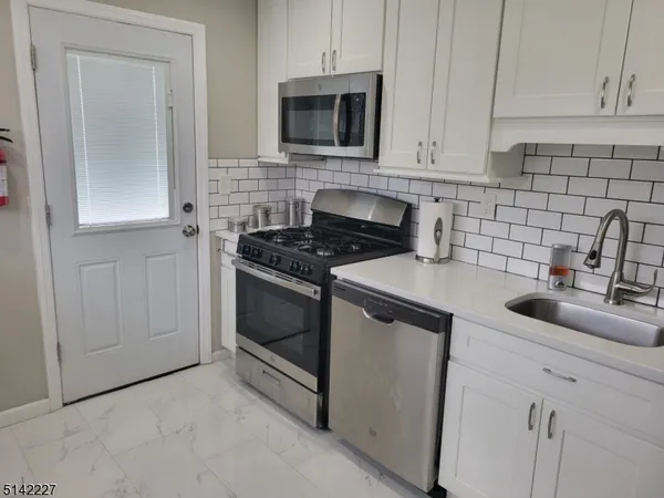 a kitchen with white cabinets and appliances