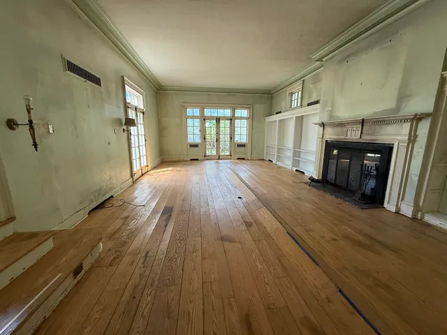 a view of an empty room with a window and wooden floor
