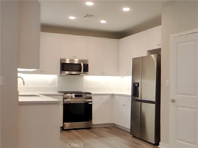 a kitchen with stainless steel appliances granite countertop a refrigerator and a stove