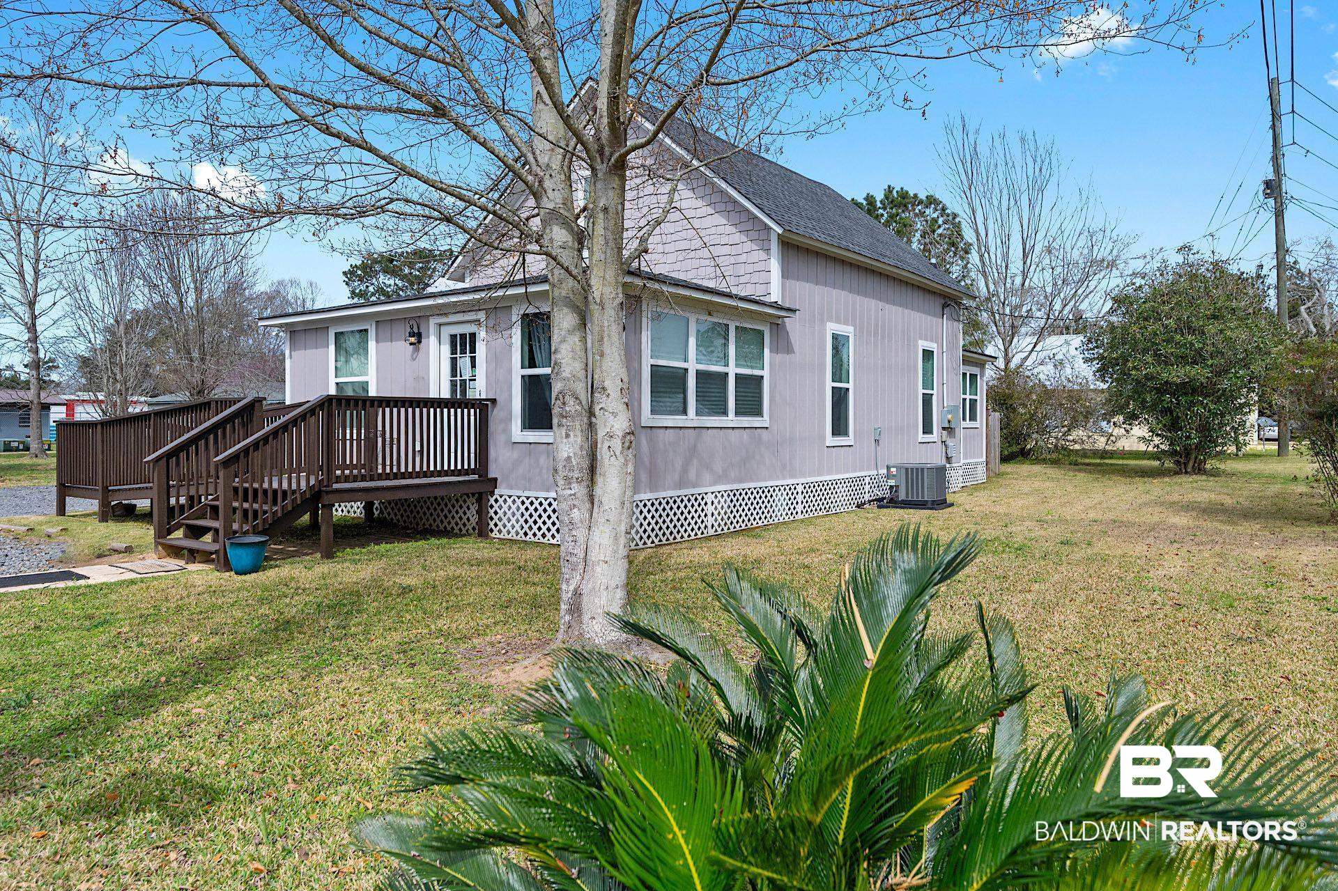 22051 Broad Street Silverhill, AL 36576 - Photo 5 of 28 View of front of home featuring a wooden deck, cooling unit, and a front lawn
