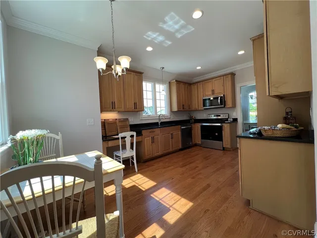 a kitchen with stainless steel appliances kitchen island granite countertop a refrigerator a stove top oven a sink dishwasher and a dining table with wooden floor