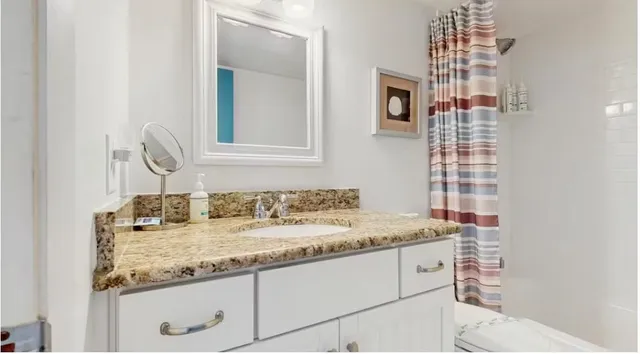 a bathroom with a granite countertop sink and a mirror