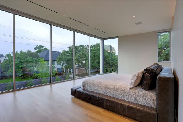 a large white kitchen with stainless steel appliances kitchen island a stove a sink a refrigerator and a dining table with wooden floor