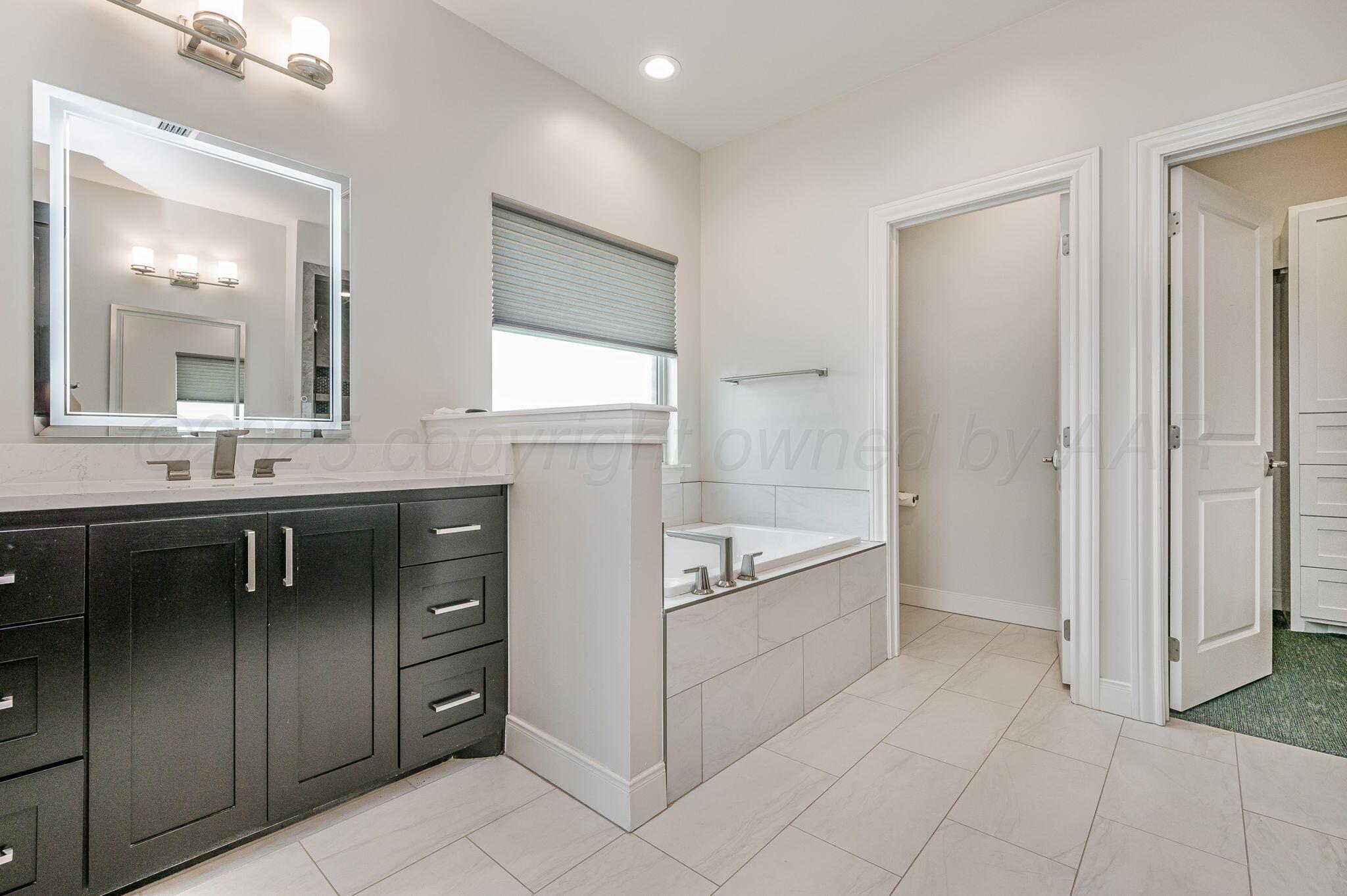 9734 Cicada Trail Amarillo, TX 79119 - Photo 17 of 34 a spacious bathroom with a granite countertop sink a mirror and a bathtub