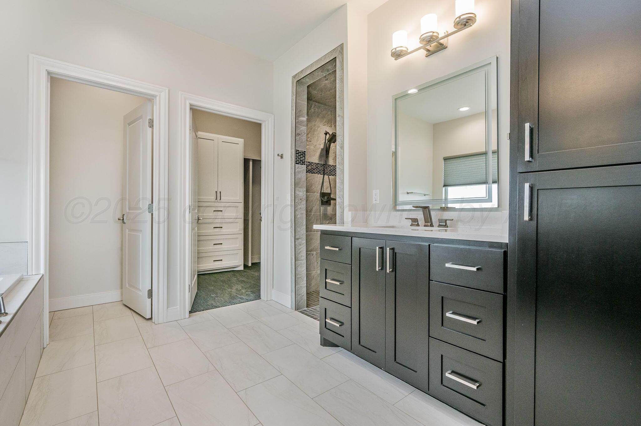 9734 Cicada Trail Amarillo, TX 79119 - Photo 18 of 34 wooden bathroom with a vanity a sink a mirror and a shower