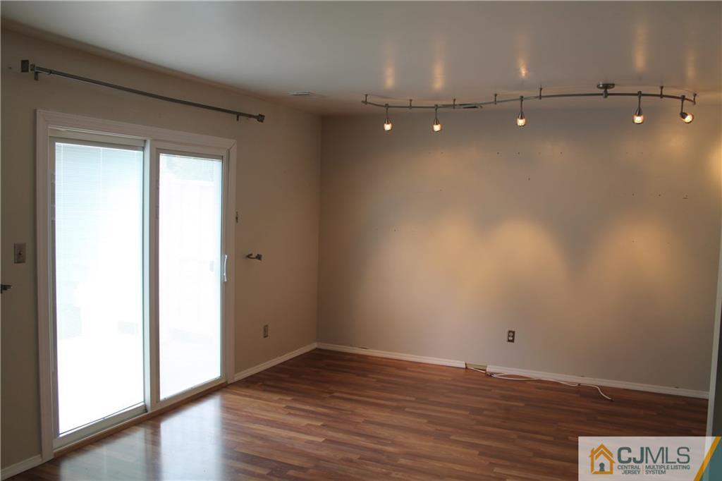 59 La Rue Lane, Unit 59 East Brunswick, NJ 08816 - Photo 12 of 17 a view of an empty room with wooden floor and a window